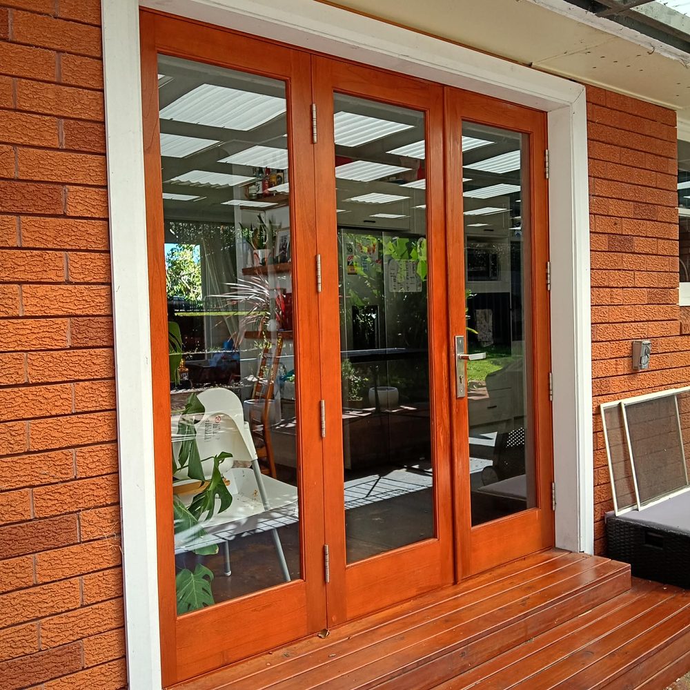 Timber-framed glass doors on a brick home, freshly cleaned and gleaming in the sun